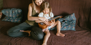 Mom helps daughter play the Ukulele